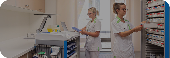Dos enfermeras organizan y preparan medicación en una sala médica limpia y bien equipada. 
